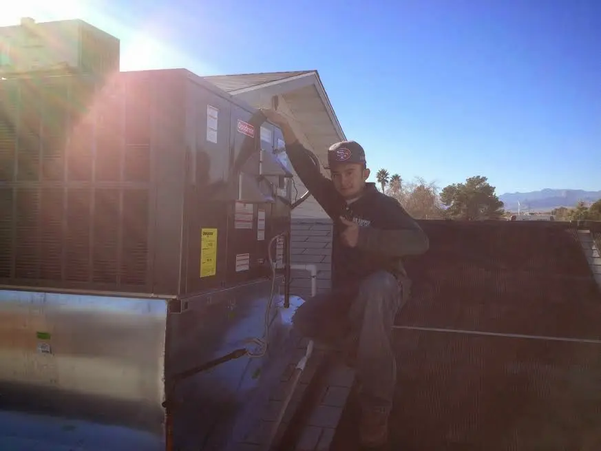 HVAC technician performing AC Tune-Up on a rooftop unit in Brandon
